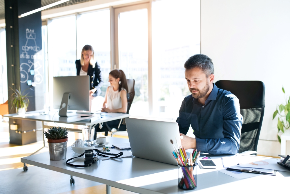 Modernes Büro mit Menschen die an einem Computer arbeiten.